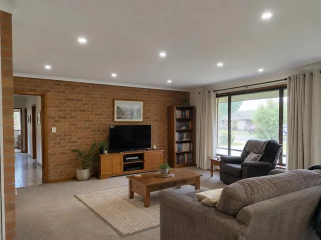 Living room with recessed ceiling downlights, brick walls, carpet and window curtains in Arcadia Vale